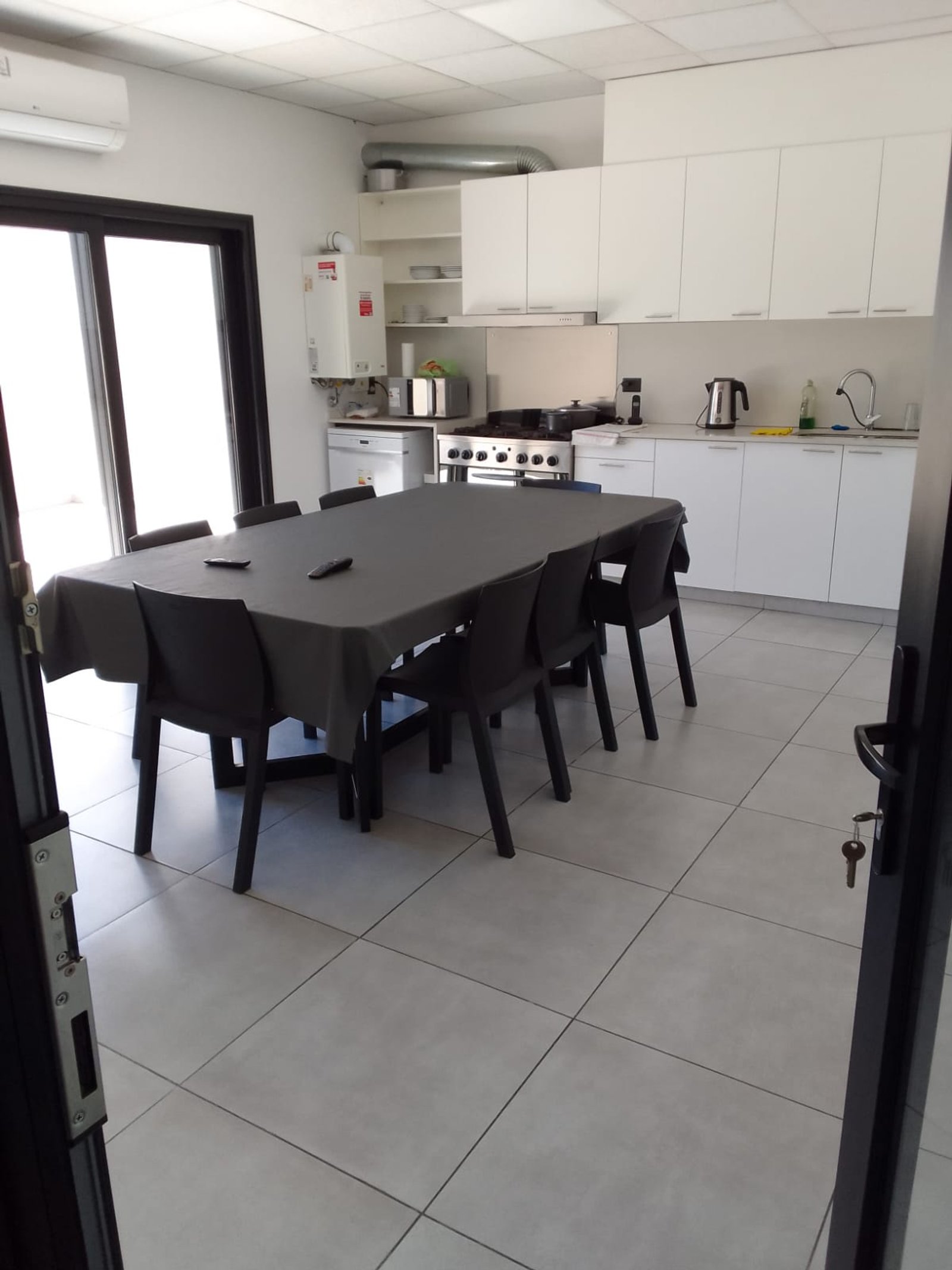 Cocina moderna con mesa de comedor y gabinetes blancos — proyecto Drogueria en Avellaneda, por Arquitecto Guido Niccoli, en B1872 Sarandí